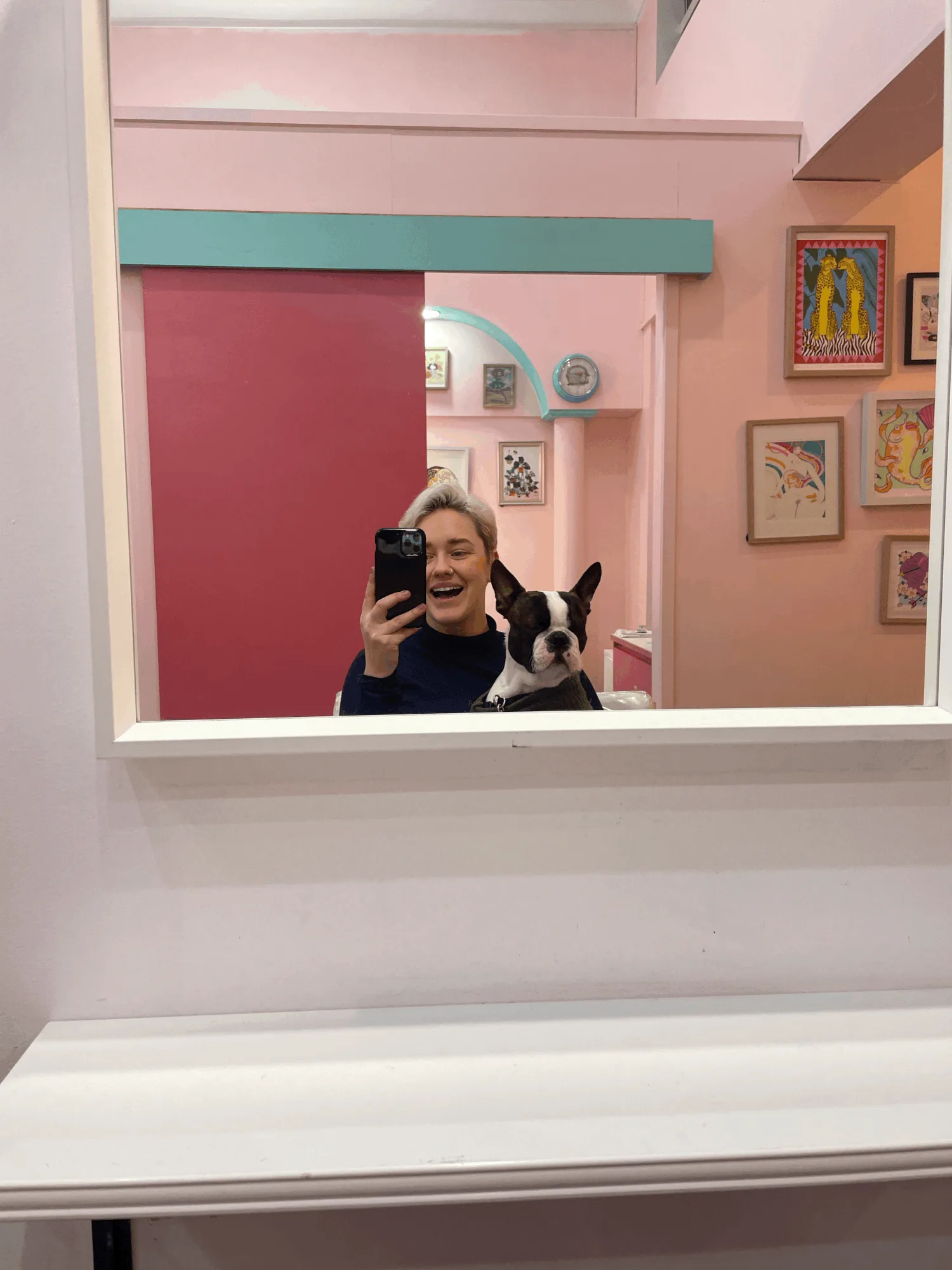 Inside Miss Jay's salon — pink walls, teal arch and beam, gallery wall of queer art prints
